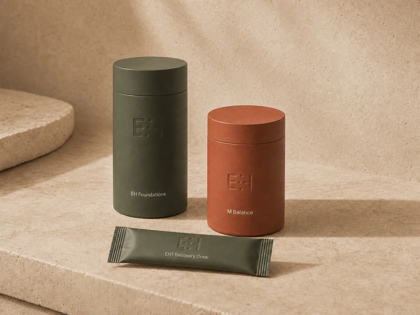 EH Foundations, M Balance, and EH1 Recovery Drink arranged on warm travertine