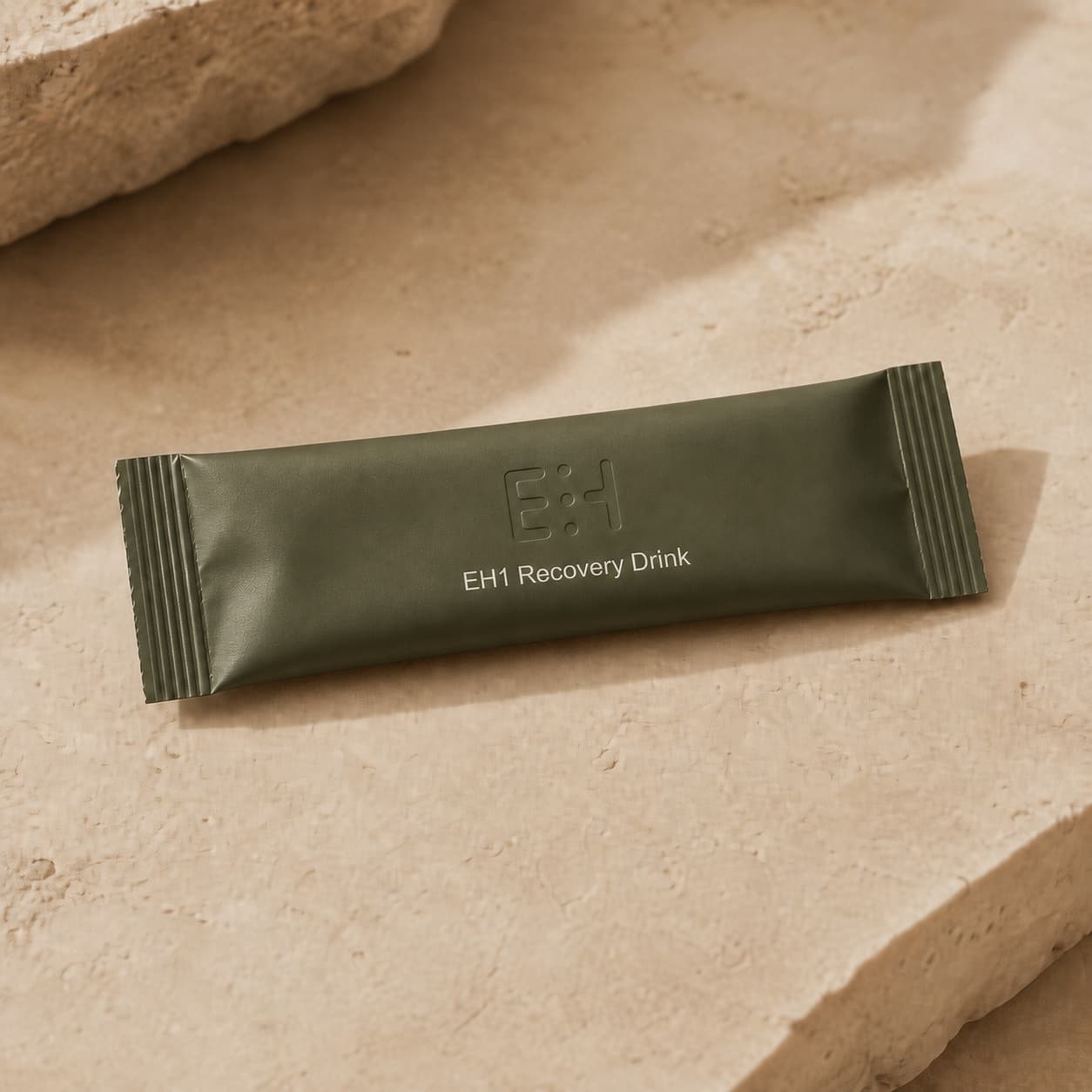 Deep-sage EH1 Recovery Drink stick pack on warm travertine